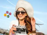 Woman with camera on holiday surrounded by currency icons